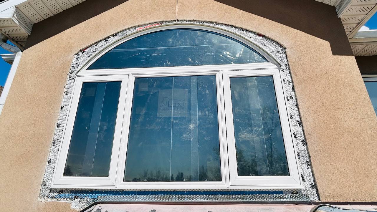 Arched window being set in rough opening — Calgary home, shimmed and taped