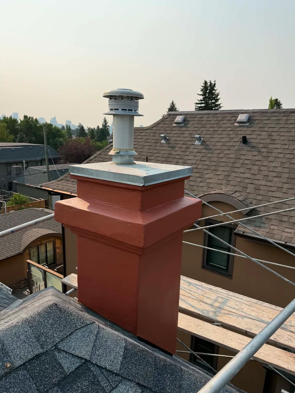 Completed red-finished chimney with rebuilt trim and a metal cap.